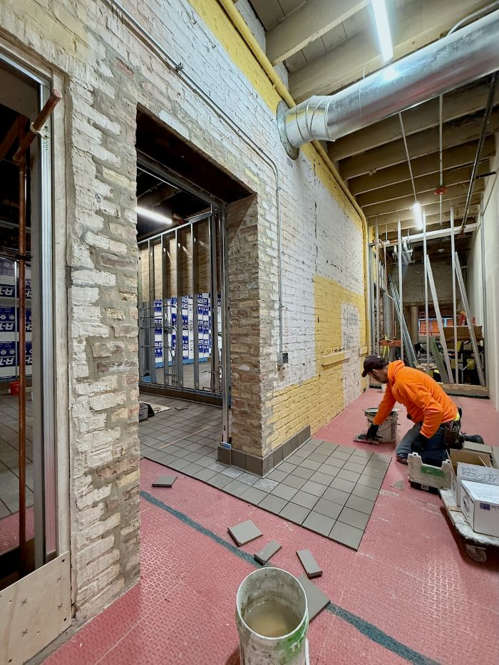 Commercial flooring installer working on a large polished concrete floor in a bright industrial space with large windows